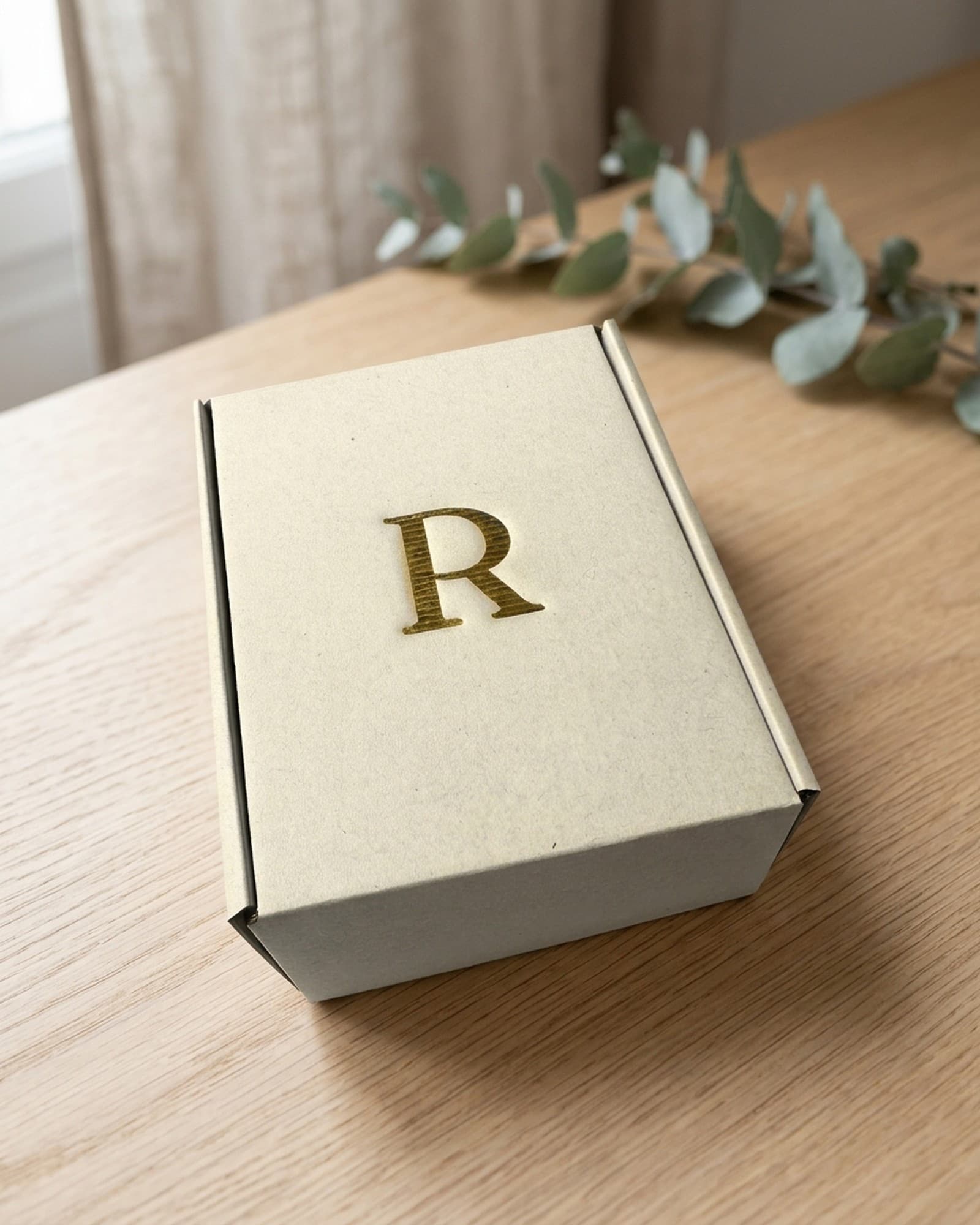 Rhealiz box, probiotic and prebiotic made in France, gold R monogram, on an oak table